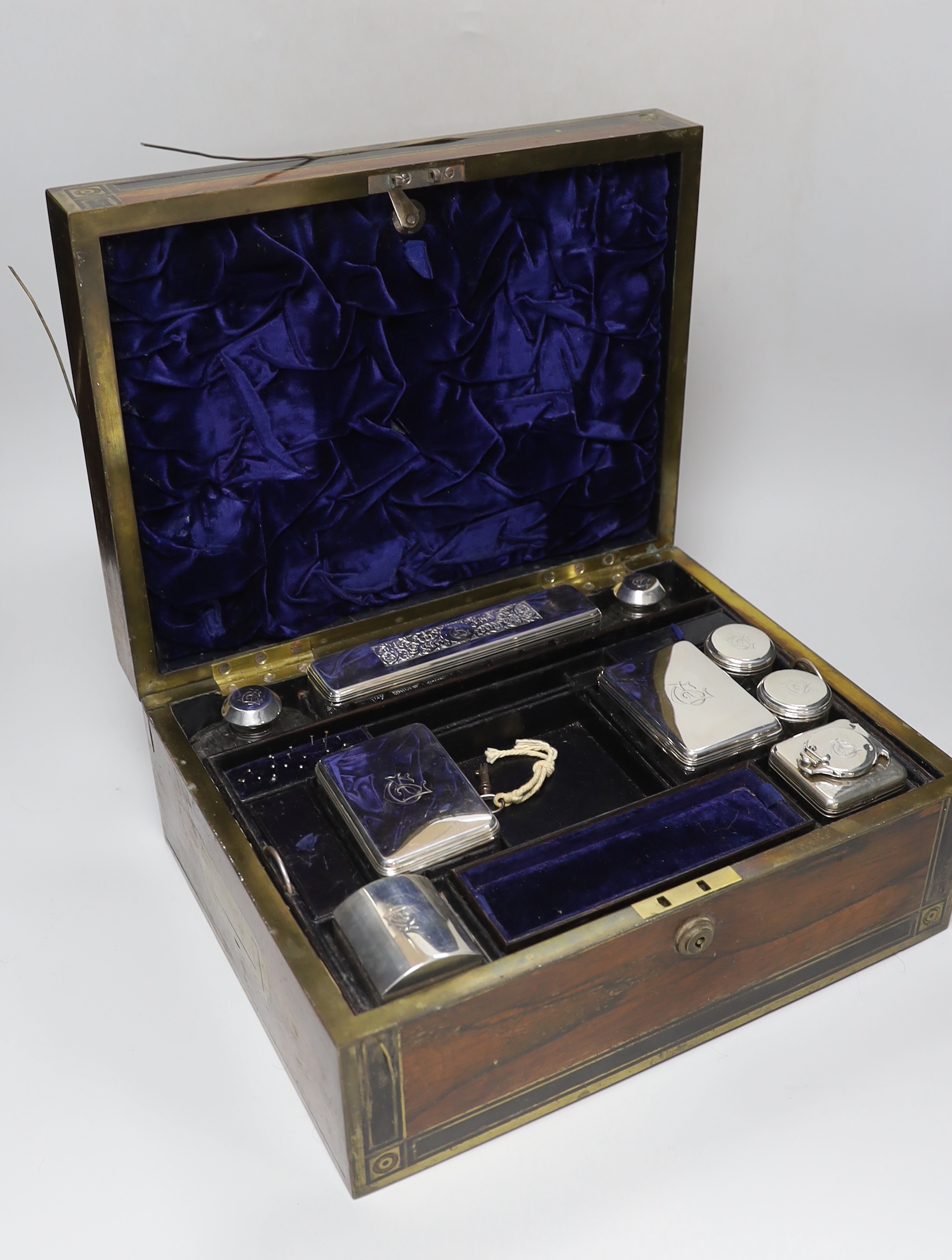 A George IV brass mounted rosewood travelling toilet box, with eleven silver mounted glass toilet jars etc, John & Archibald Douglas, London, 1822, with engraved monograms, four caps unmarked, box 34.1cm.